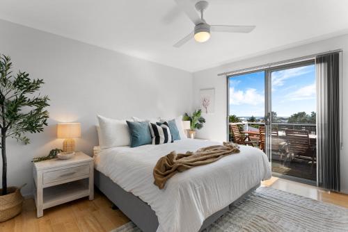 a white bedroom with a bed and a large window at Hazel Beach House - Ocean Views & Coastal Charm in Goolwa South
