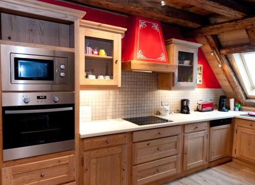 - une cuisine avec des placards en bois et un four micro-ondes dans l'établissement Gite des Frères Mertian, à Ribeauvillé