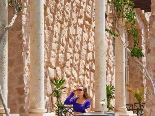 a woman sitting on a bench in front of a building at Mövenpick Resort & Residences Aqaba in Aqaba