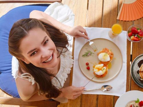 a woman sitting at a table with a plate of food at Mövenpick Resort & Residences Aqaba in Aqaba