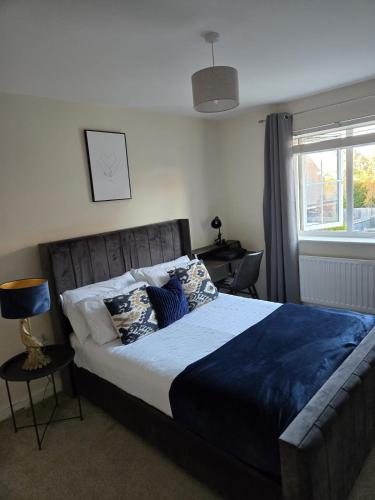 een slaapkamer met een bed met blauwe lakens en een raam bij Work & Family Haven in Ashford
