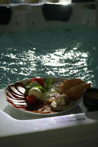 een bord eten op een tafel naast het water bij Sky Spa Penthouse Suite with Hot Tub Zlatibor in Zlatibor