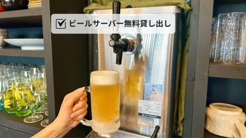 a person holding a glass of beer in a machine at 尾道stay源 -MINAMOTO- in Kaneyoshi
