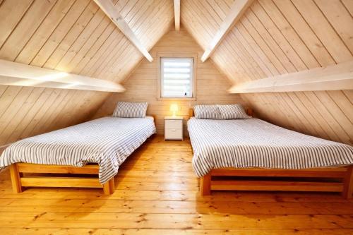 two beds in a room with a wooden ceiling at Domeczki Blaneczki Wicie - domki letniskowe nad morzem in Wicie