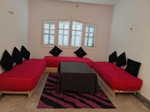 a living room with two red couches and a window at Villa harhora in Temara