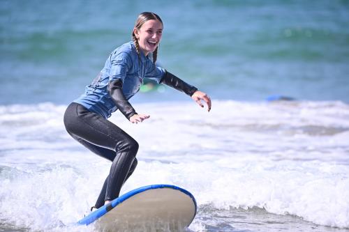 a woman riding a wave on a surfboard in the ocean at Mabidi Surf Taghazout in Taghazout