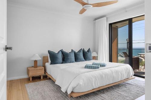 une chambre blanche avec un grand lit avec des oreillers bleus dans l'établissement Panorama, Gerroa, South Coast, à Gerroa