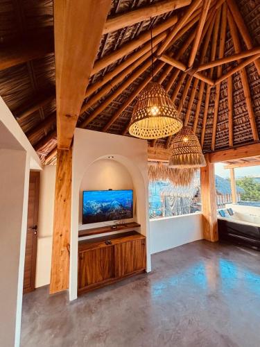 a living room with a flat screen tv and a chandelier at Punta Arena Surf Suites in Puerto Escondido