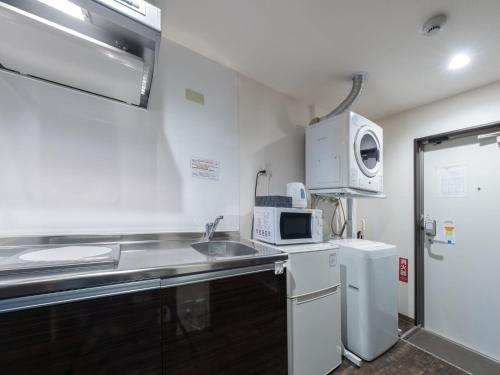 a small kitchen with a sink and a microwave at Hote Io Lite in Nago