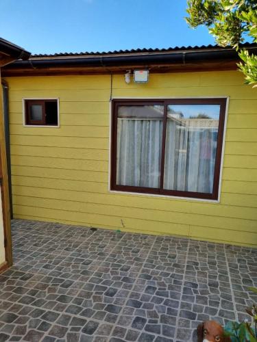 een geel huis met een hond er voor bij Departamento Mar y Viento in Pichilemu