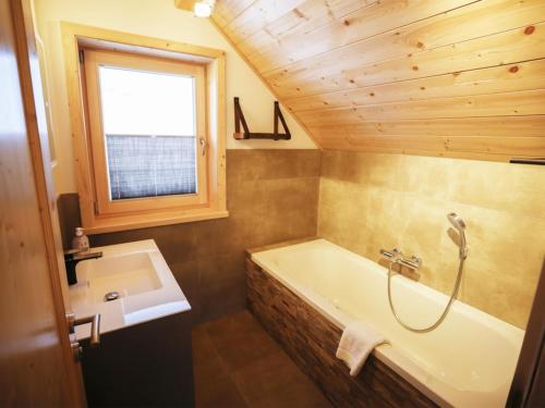 een badkamer met een ligbad en een wastafel bij Designchalets Falkertsee in Ebene Reichenau