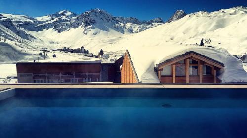 a building with snow covered mountains in the background at Hôtel les Campanules by Les Etincelles in Tignes