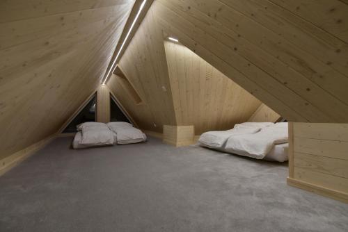 two beds in a attic room with wooden walls at Wierchy Resort 21B by AWapartaments in Zakopane
