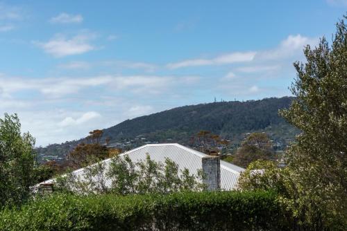 a white building with a mountain in the background at Spacious beachside family home in Rosebud