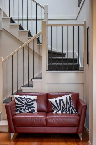 a brown leather couch in a living room with stairs at Spacious beachside family home in Rosebud