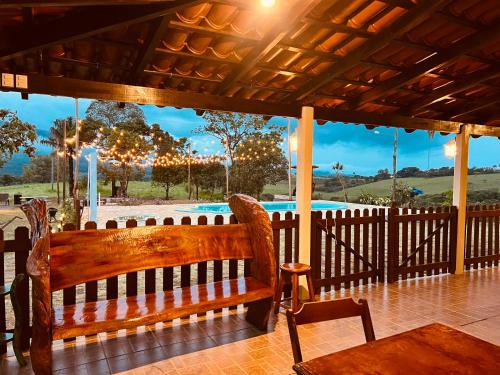 een houten bank op een veranda met uitzicht op een zwembad bij Pousada Horizonte da Canastra in São Roque de Minas