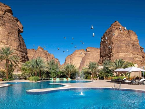 uma piscina no deserto com montanhas ao fundo em Shaden Resort em Al Ula