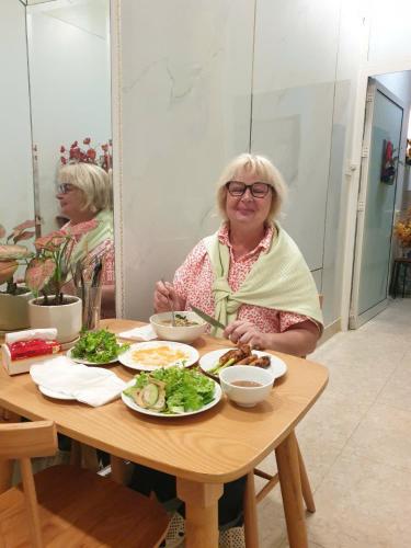een vrouw die aan een tafel zit met een bord eten bij Lavande Hue Homestay in Hue