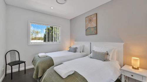 twee bedden in een witte kamer met een raam bij Bella Callala in Callala Beach