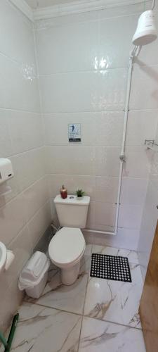 een witte badkamer met toilet en douche bij Casa térrea a 1km da praia com ar condicionado in Bertioga