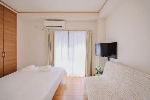 ein weißes Schlafzimmer mit einem Bett und einem Fernseher in der Unterkunft 3 min JR Direct to Skytree Asakusa Shinjuku Sea Heim in Tokio
