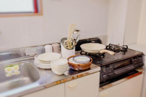 eine Küchentheke mit Tellern, Schalen und einer Spüle in der Unterkunft 3 min JR Direct to Skytree Asakusa Shinjuku Sea Heim in Tokio