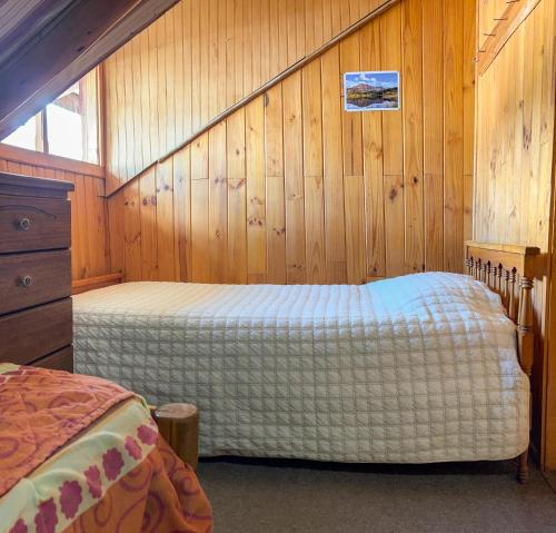 a bedroom with a bed in a wooden wall at Hospedaje La Cascada in Futaleufú