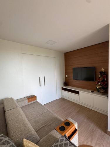 a living room with a couch and a flat screen tv at Apto completo no Vista Azul - Varanda com vista da Pedra Azul in Pedra Azul