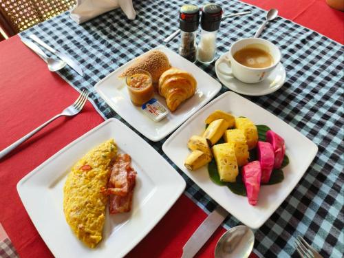 a table with three plates of breakfast foods and a cup of coffee at Au Cabaret Vert in Battambang