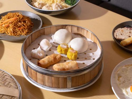 AKI Hotel Hong Kong - MGallery Collection في هونغ كونغ: وعاء من الطعام على طاولة مع أطباق من الطعام