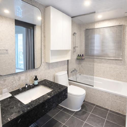 a bathroom with a sink and a toilet and a tub at Magnum Nampo Hotel in Busan