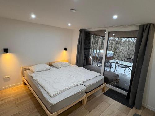 a bedroom with a large bed and a balcony at Chalet in the woods with Nordic bath in Manhay