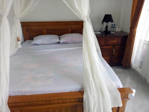 a bedroom with a bed with a mosquito net at Aris Homestay and Warung Made in Munduk