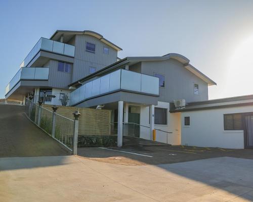 a large building with a staircase in a parking lot at Boatshed Motel Apartments in Mount Maunganui