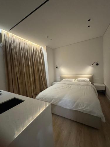 une chambre blanche avec un grand lit et une fenêtre dans l'établissement Tirana Square Apartments, à Tirana
