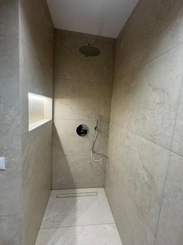 La salle de bains est pourvue d'une douche et d'un mur en pierre. dans l'établissement Tirana Square Apartments, à Tirana