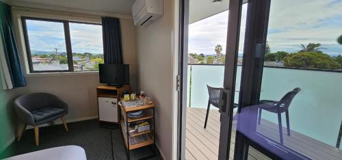 a hotel room with a balcony with a view of the water at Boatshed Motel Apartments in Mount Maunganui