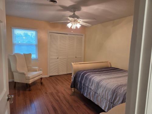 a bedroom with a bed and a chair and a ceiling fan at Walk to Augusta National with Pool, Housekeeper, and Utilities Included in Augusta