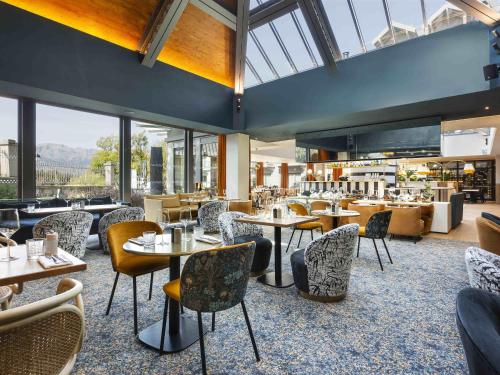 een restaurant met tafels, stoelen en ramen bij Le Saint Gervais Hotel & Spa Handwritten Collection in Saint-Gervais-les-Bains