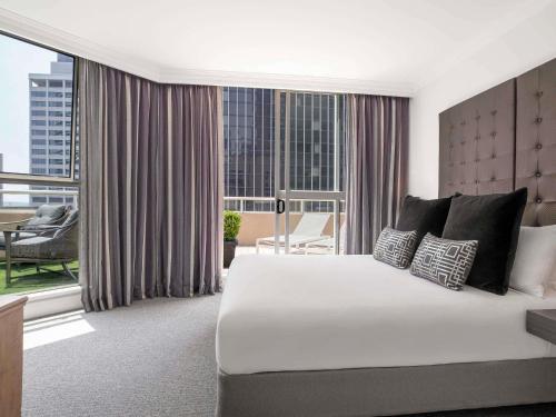 um quarto com uma cama grande e uma janela grande em Mantra 2 Bond Street em Sidney