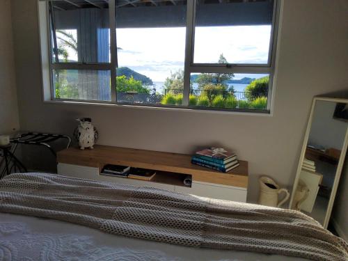 a bedroom with a bed and a window with a view at Te Kouma Sunsets in Coromandel Town