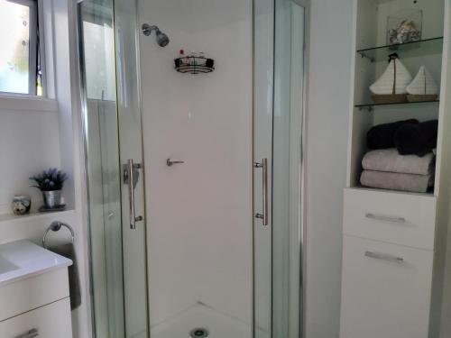 a shower with a glass door in a bathroom at Te Kouma Sunsets in Coromandel Town