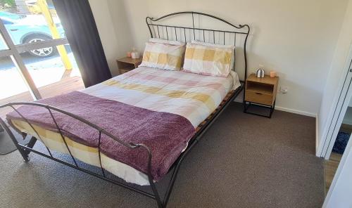 a bedroom with a bed with a metal frame at Best of Both Worlds Between City & Sea Holiday House in Nelson