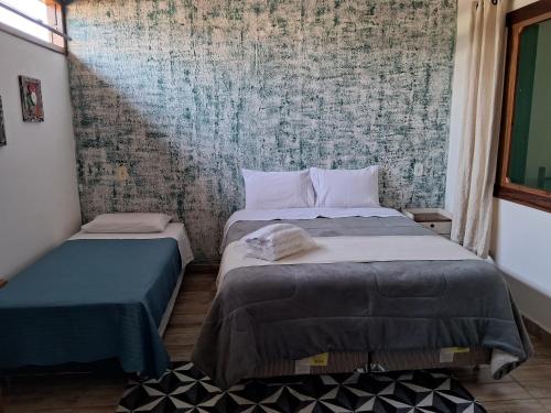 twee bedden in een kamer met muurschildering bij Pouso C&L in Tiradentes