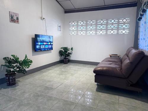 a waiting room with a leather couch and a flat screen tv at Baboo Guesthouse in Chiang Dao