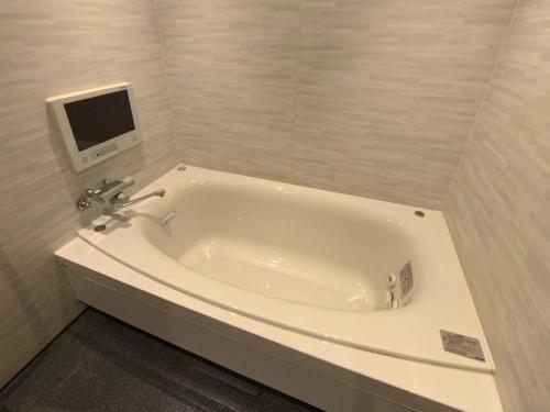a bath tub in a bathroom with a tv on the wall at ヴァンヴェールアネックス in Kyoto