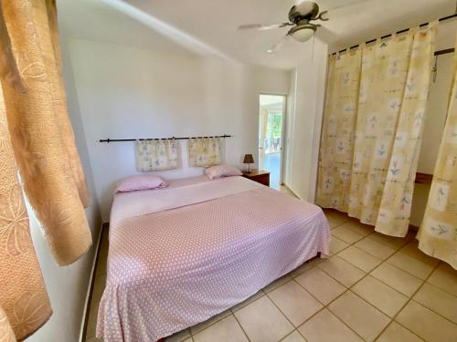 een slaapkamer met een bed en een plafondventilator bij Casa Blanca Samaná - Las Galeras in Las Galeras