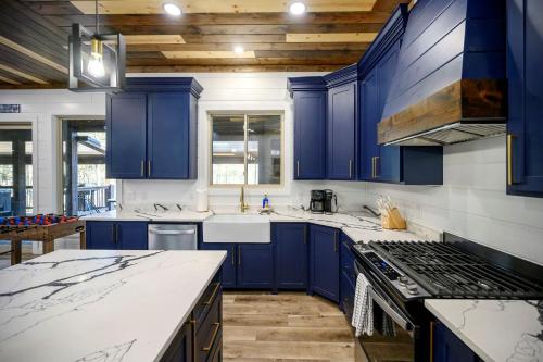 a blue kitchen with white counters and blue cabinets at Chillax Inn The River For 19 in Broken Bow