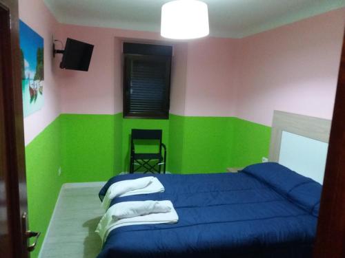 1 dormitorio con 1 cama azul y paredes de color verde y rosa en Apartamentos Vigar, en Segovia
