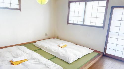 zwei Betten in einem Zimmer mit zwei Fenstern in der Unterkunft 富士見旅館206 in Fujiyoshida